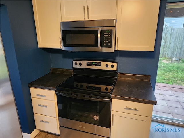 kitchen featuring appliances with stainless steel finishes, light tile patterned floors, and white cabinets