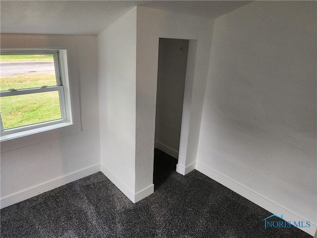 spare room featuring dark colored carpet