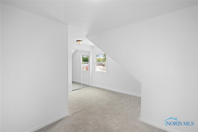 bonus room featuring lofted ceiling and light carpet