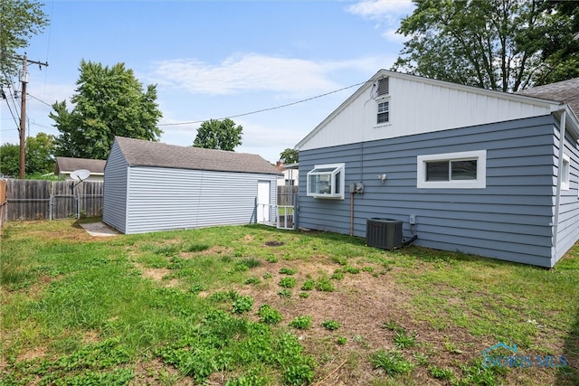 back of house with cooling unit, a storage unit, and a lawn