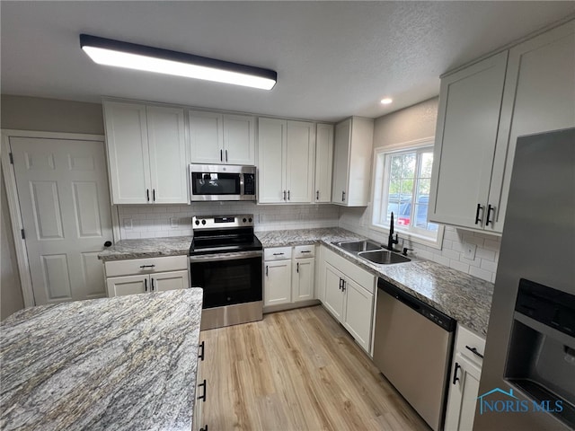 kitchen featuring white cabinets, backsplash, stainless steel appliances, and sink