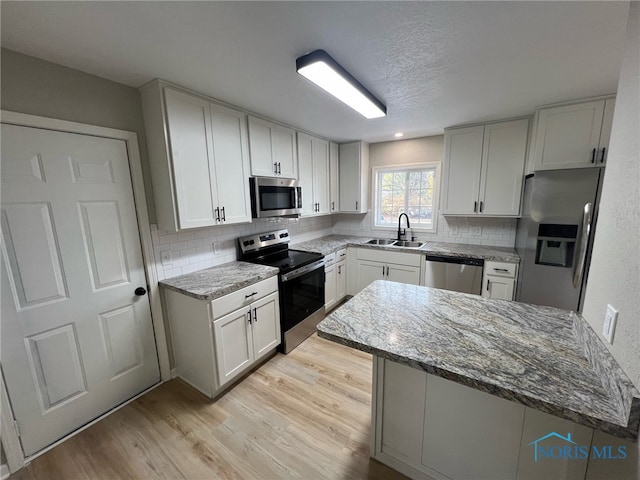 kitchen with white cabinets, stone countertops, sink, and stainless steel appliances