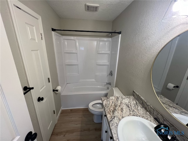 full bathroom featuring bathing tub / shower combination, a textured ceiling, toilet, vanity, and hardwood / wood-style flooring