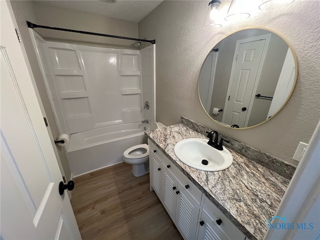 full bathroom with vanity,  shower combination, a textured ceiling, wood-type flooring, and toilet