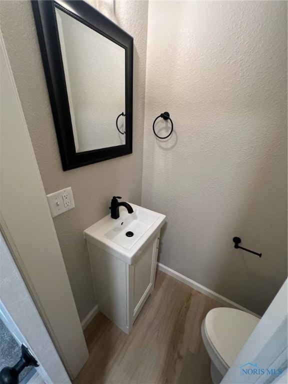 bathroom featuring vanity, hardwood / wood-style flooring, and toilet