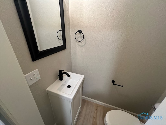 bathroom featuring vanity, wood-type flooring, and toilet