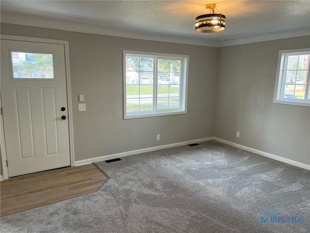 carpeted entryway featuring a textured ceiling