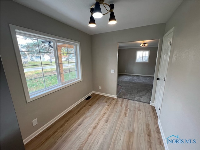 unfurnished dining area with a chandelier and light hardwood / wood-style flooring