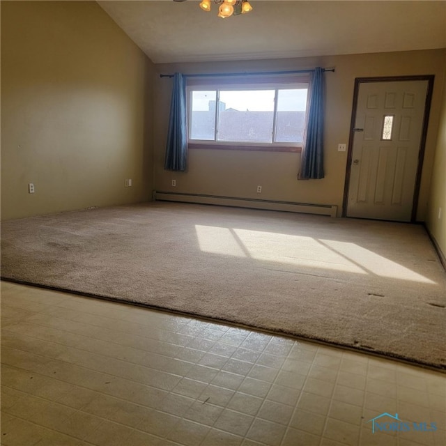 carpeted empty room with baseboard heating and vaulted ceiling