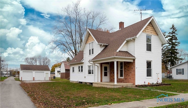 view of front facade featuring a garage, an outdoor structure, a front yard, and covered porch