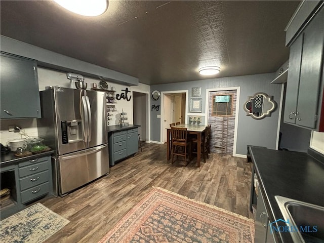 kitchen with dark wood-type flooring, sink, a textured ceiling, and stainless steel fridge with ice dispenser