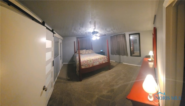 bedroom featuring a barn door and dark colored carpet