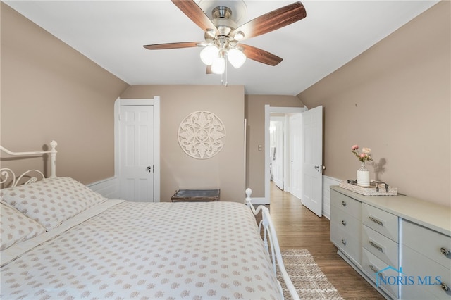 bedroom with ceiling fan, dark wood-type flooring, and vaulted ceiling