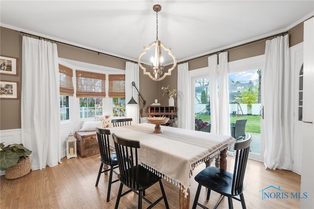 dining space with light hardwood / wood-style floors, a wealth of natural light, and an inviting chandelier