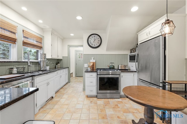 kitchen with white cabinets, pendant lighting, dark stone countertops, and appliances with stainless steel finishes