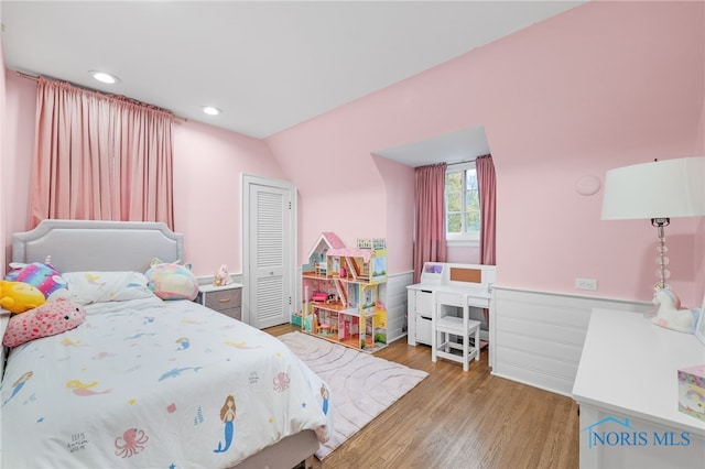 bedroom with vaulted ceiling, a closet, and light hardwood / wood-style flooring