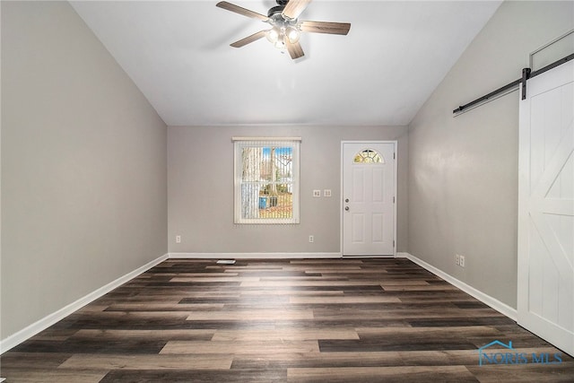 foyer with a barn door, dark hardwood / wood-style floors, lofted ceiling, and ceiling fan