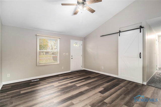 foyer entrance with dark wood-type flooring, ceiling fan, lofted ceiling, and a barn door