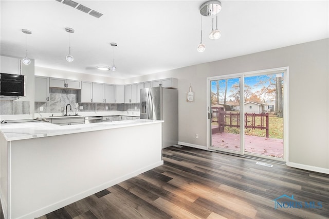 kitchen with decorative light fixtures, dark wood-type flooring, light stone countertops, and appliances with stainless steel finishes