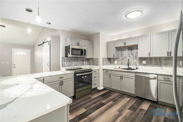 kitchen featuring appliances with stainless steel finishes, a barn door, hanging light fixtures, and gray cabinetry