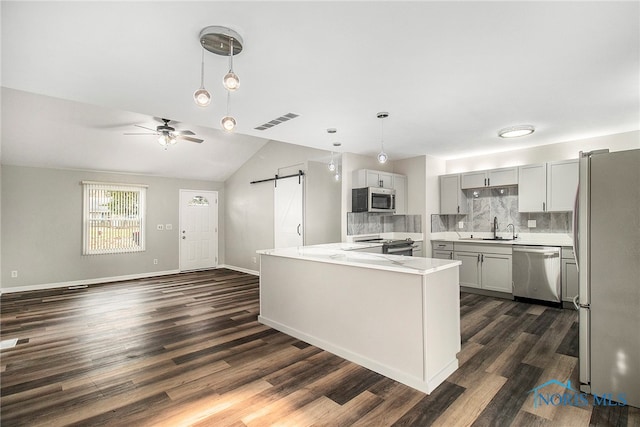 kitchen featuring lofted ceiling, sink, tasteful backsplash, appliances with stainless steel finishes, and a barn door