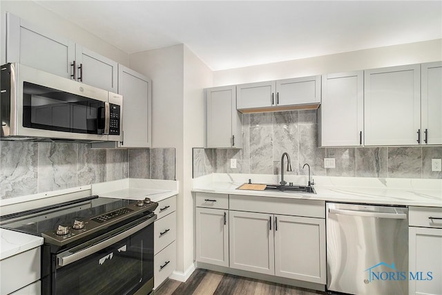 kitchen with light stone counters, stainless steel appliances, dark hardwood / wood-style floors, and sink