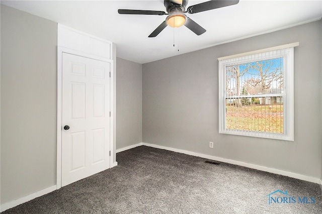 unfurnished room with dark colored carpet and ceiling fan