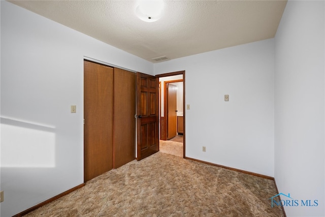 unfurnished bedroom featuring a closet, light colored carpet, and a textured ceiling