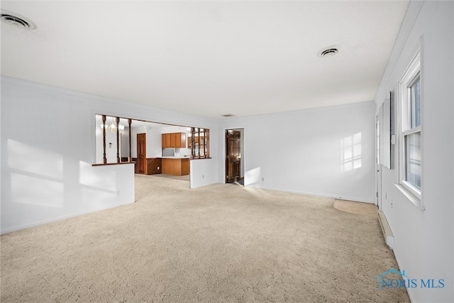 unfurnished living room with crown molding and light carpet