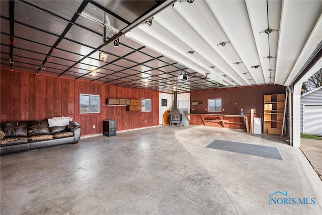 garage featuring wood walls, a wood stove, and a garage door opener