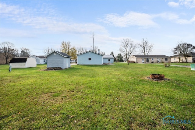 view of yard with a fire pit and an outdoor structure