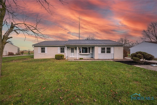 ranch-style house featuring a lawn and covered porch