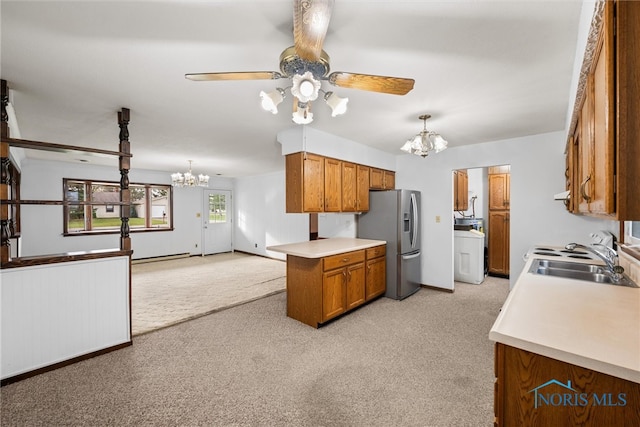 kitchen with pendant lighting, stainless steel fridge, washer / dryer, and sink