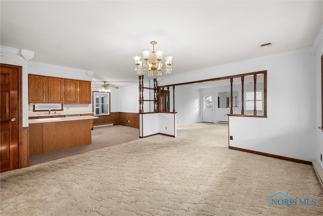 kitchen featuring decorative light fixtures, light colored carpet, crown molding, and wood walls