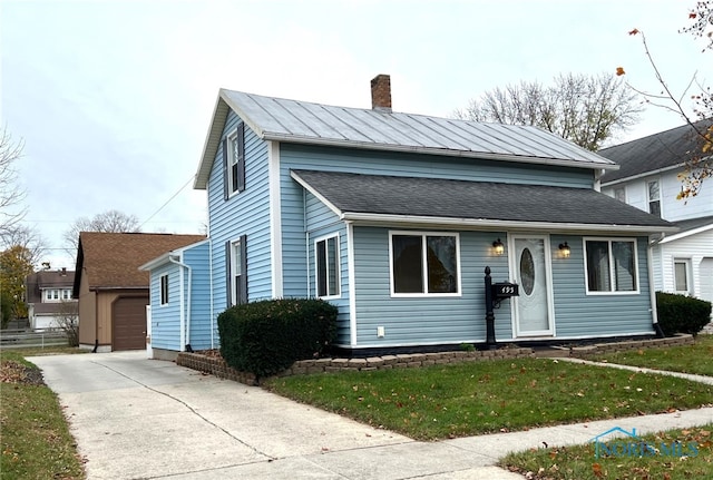 view of front of house with a front yard, a garage, and an outdoor structure