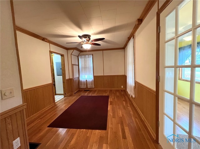 empty room with ceiling fan, plenty of natural light, wood-type flooring, and crown molding