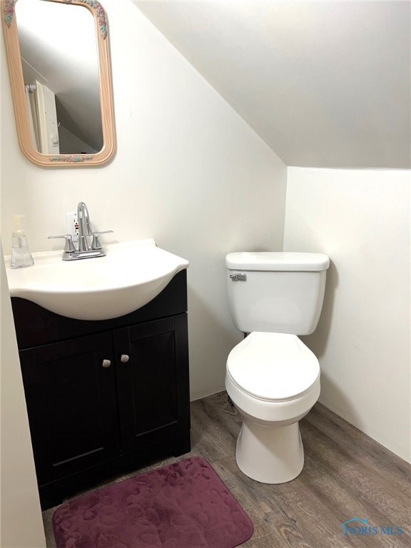 bathroom featuring vanity, wood-type flooring, lofted ceiling, and toilet