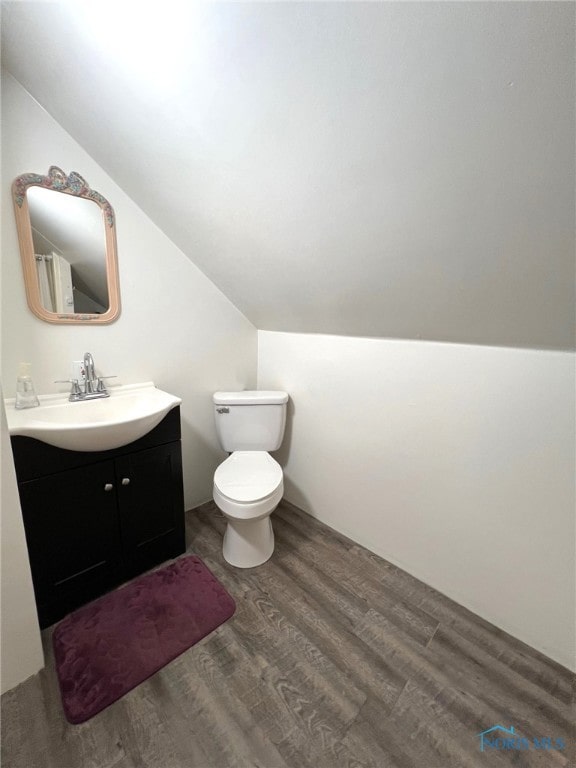 bathroom with toilet, vanity, vaulted ceiling, and hardwood / wood-style flooring