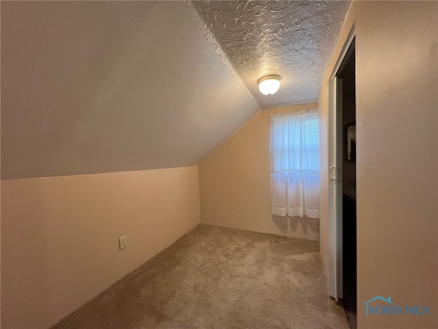 bonus room featuring light carpet, a textured ceiling, and vaulted ceiling