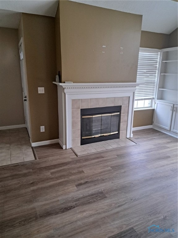 unfurnished living room featuring light wood-type flooring and a tile fireplace