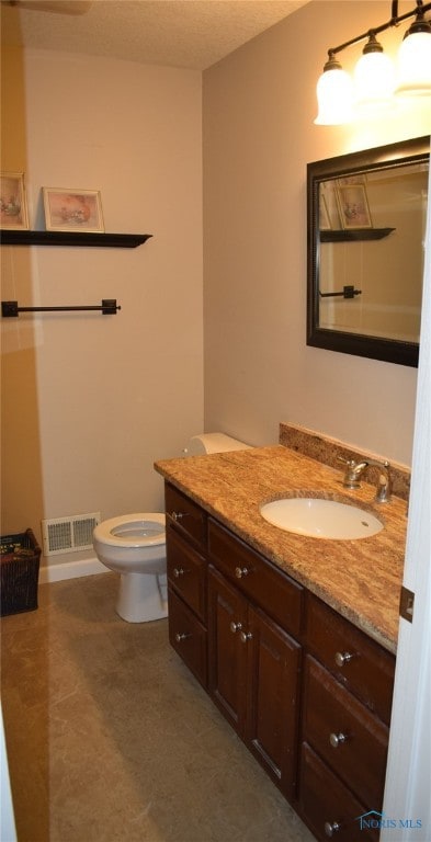 bathroom with vanity, a textured ceiling, and toilet