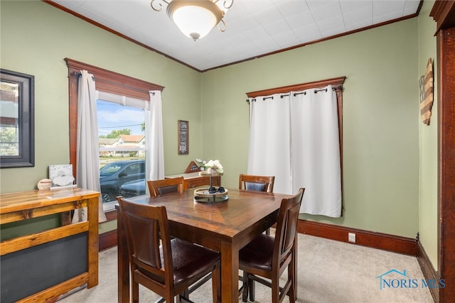 dining space with crown molding and light colored carpet