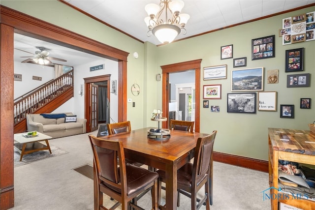 dining room with ceiling fan with notable chandelier, crown molding, and light carpet