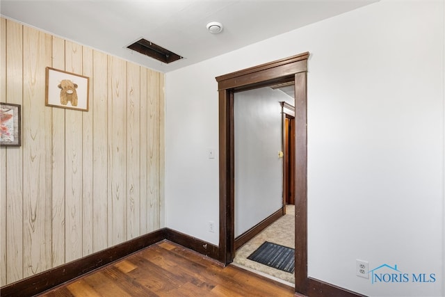 unfurnished room with wood walls and dark hardwood / wood-style floors