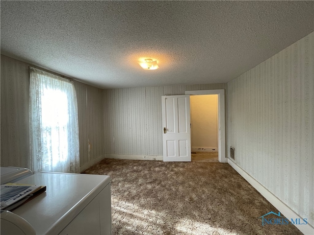 empty room featuring washing machine and clothes dryer, carpet, and a textured ceiling