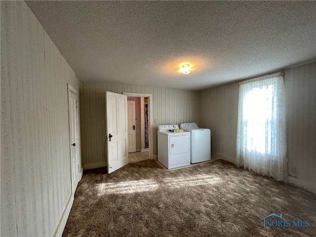 laundry room featuring a textured ceiling, washing machine and dryer, and dark carpet