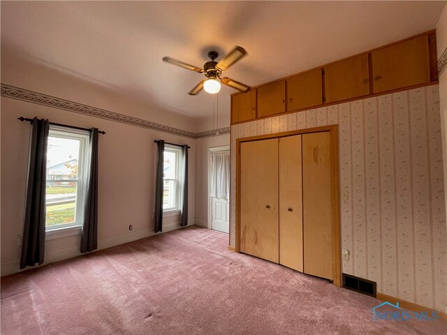 unfurnished bedroom featuring light carpet, a closet, and ceiling fan