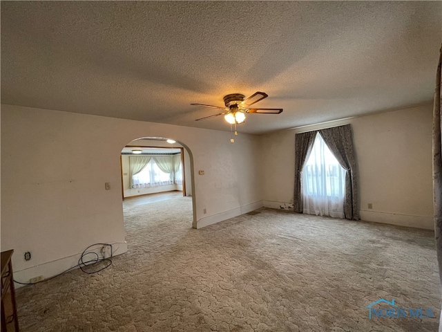 spare room featuring a textured ceiling, light colored carpet, a wealth of natural light, and ceiling fan