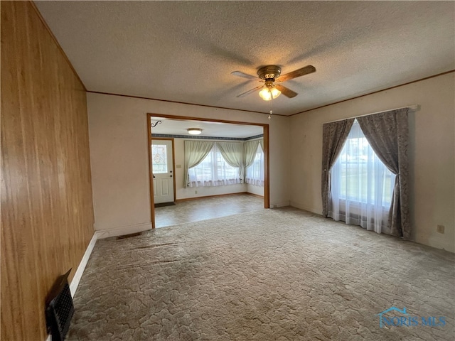 empty room featuring a wealth of natural light, wooden walls, and a textured ceiling