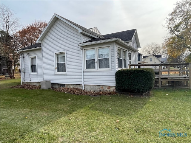 view of side of property featuring central AC unit and a yard